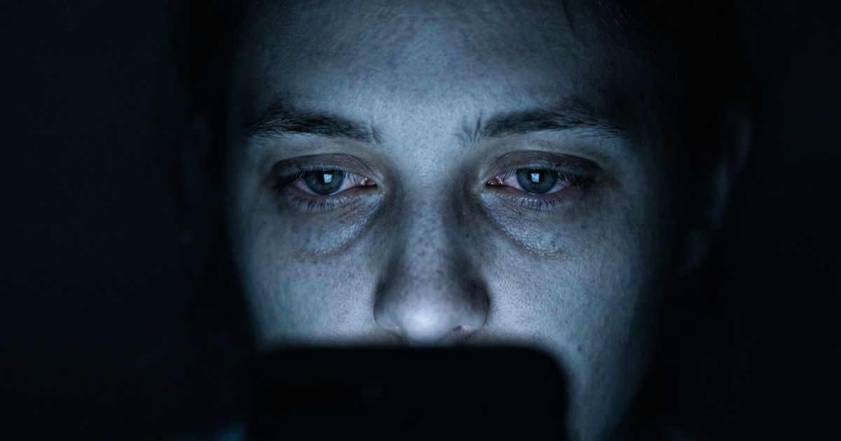 Person scrolling their phone in bed in the dark — the doomscrolling habit loop